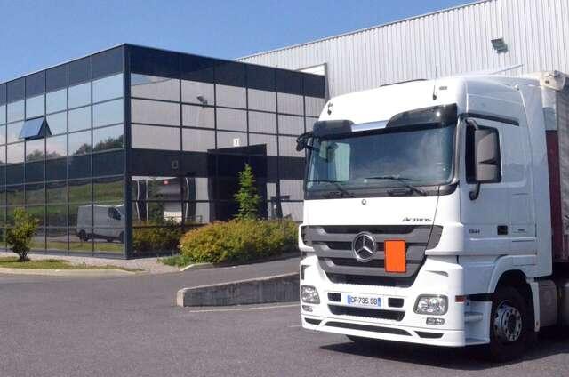 Un camion de transport stationné devant un bâtiment à La Roche-sur-Foron.