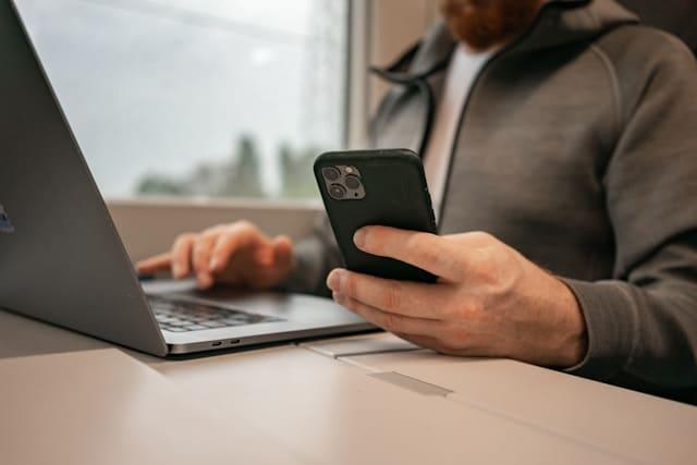 Un homme consulte son téléphone portable tout en travaillant.