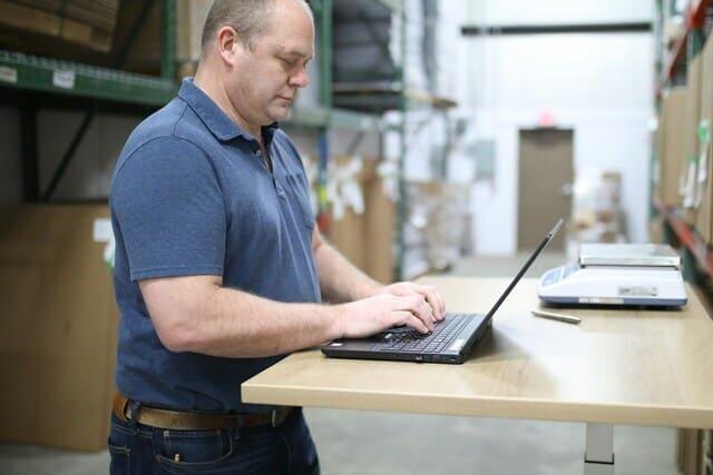 Un homme travaille sur son ordinateur portable dans un entrepôt de stockage et logistique.