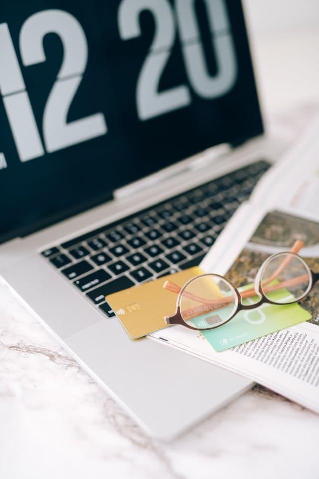 Un ordinateur avec un magazine et des cartes de crédit posé dessus.