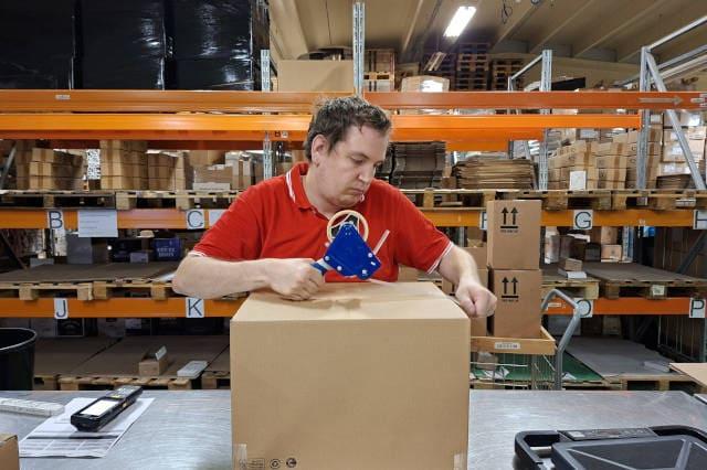 Un logisticien emballe un carton de marchandise ecommerce