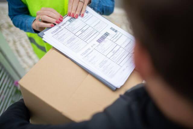 Un livreur fais signé des documents pendant la remise d'un colis
