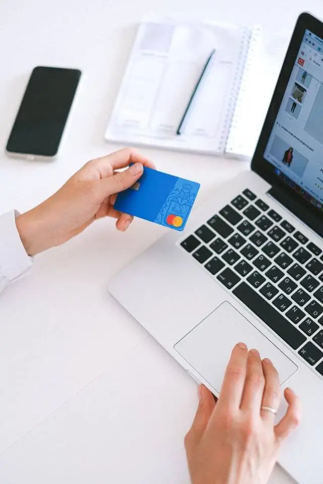 Une personne tient sa carte de crédit pendant un achat en ligne.
