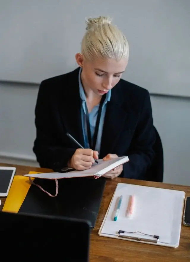 Une secrétaire prend des notes sur un carnet.