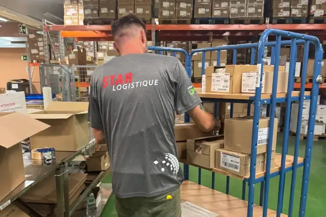 Une personne amène les colis sur un chariot.