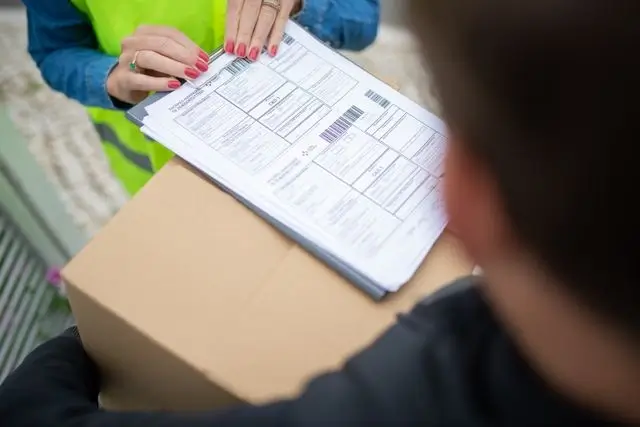 Un livreur fais signé des documents pendant la remise d'un colis.